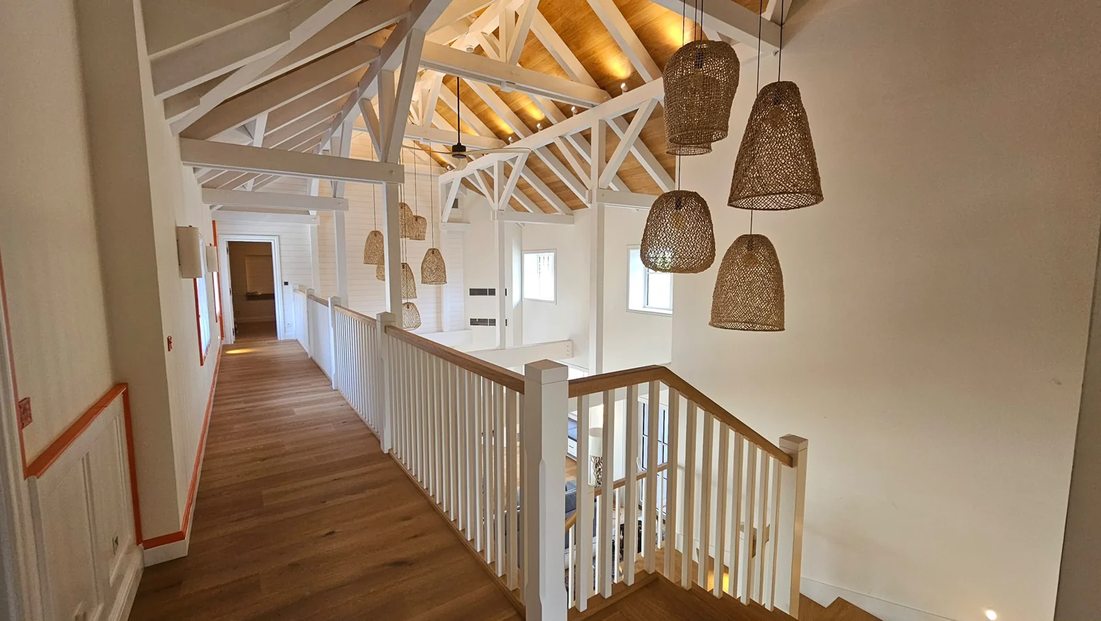 Bílé zábradlí, dřevěné prvky a otevřená galerie v podkroví.
